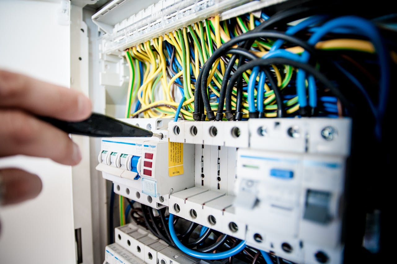 heros-img Hand of electrician working on a circuit breaker panel with colorful wires, ensuring safe electrical connections.